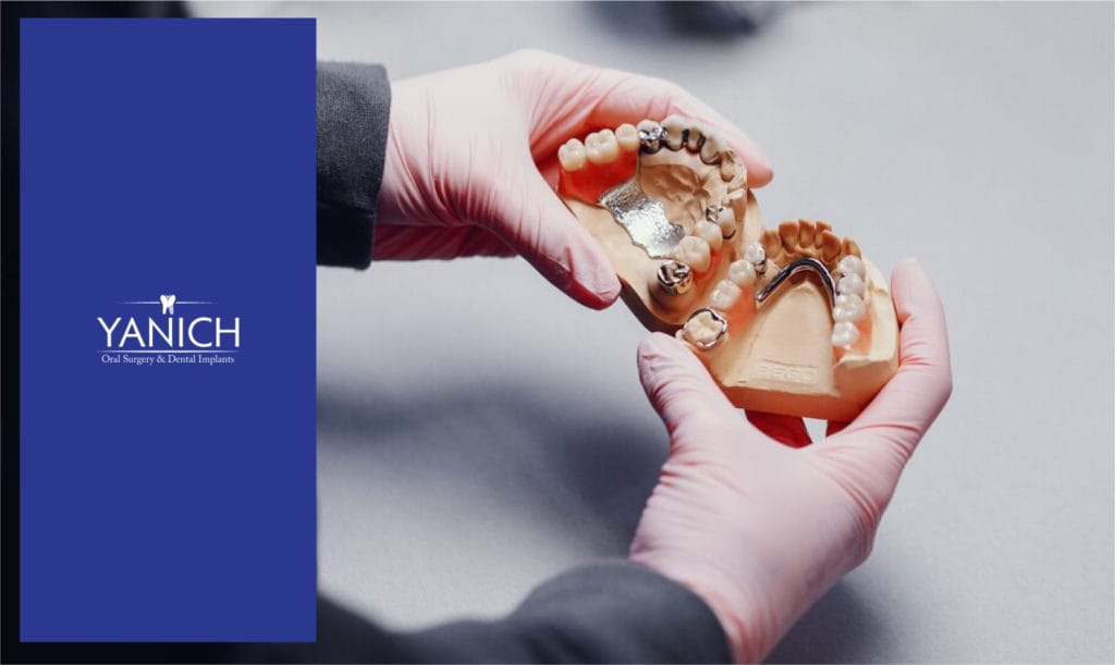 hands holding fake teeth with retainer in gums