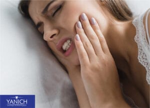 Woman experiencing wisdom tooth pain holding her jaw