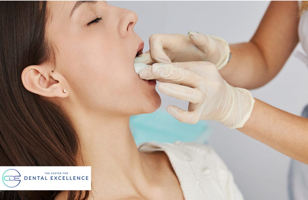 Dentist placing gauze pad in patient’s mouth to help stop bleeding and promote healing after an oral surgery.
