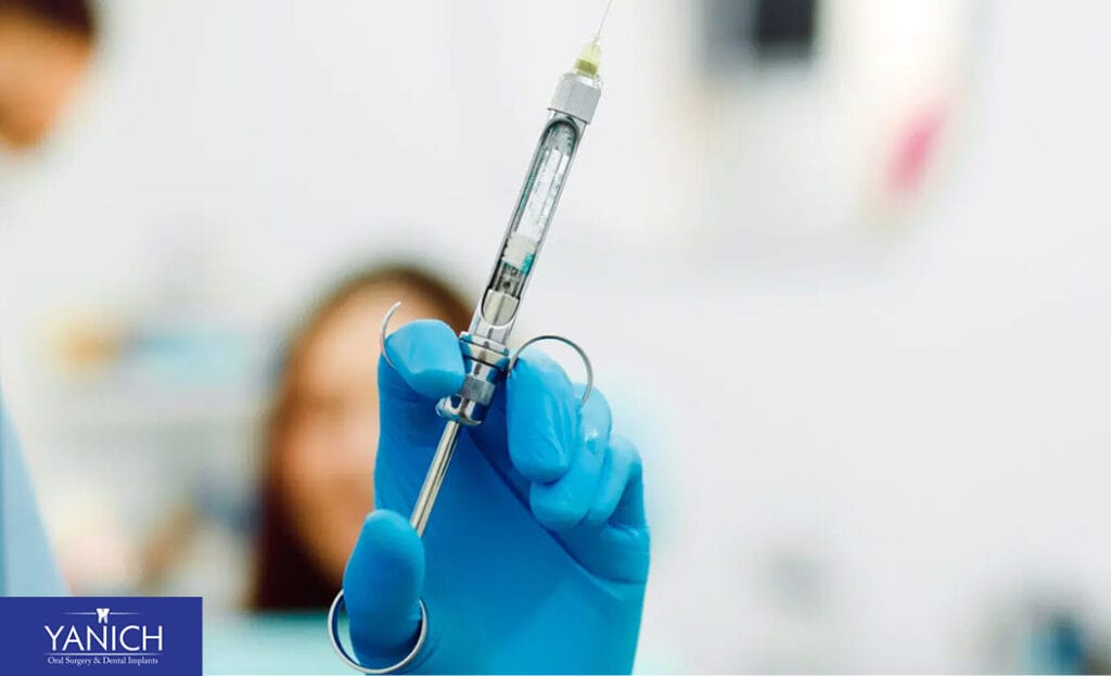 Close-up of a gloved dentist’s hand holding a dental anesthesia syringe prepared for use during an oral surgery procedure at a modern dental practice.